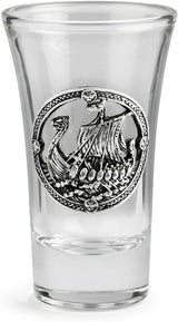 A clear glass shot glass featuring a pewter Viking ship medallion on the front