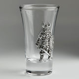 A clear glass shot glass featuring an embossed pewter Viking warrior holding a shield and sword