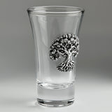 A clear glass shot glass featuring a detailed pewter tree of life emblem