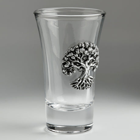 A clear glass shot glass featuring a detailed pewter tree of life emblem
