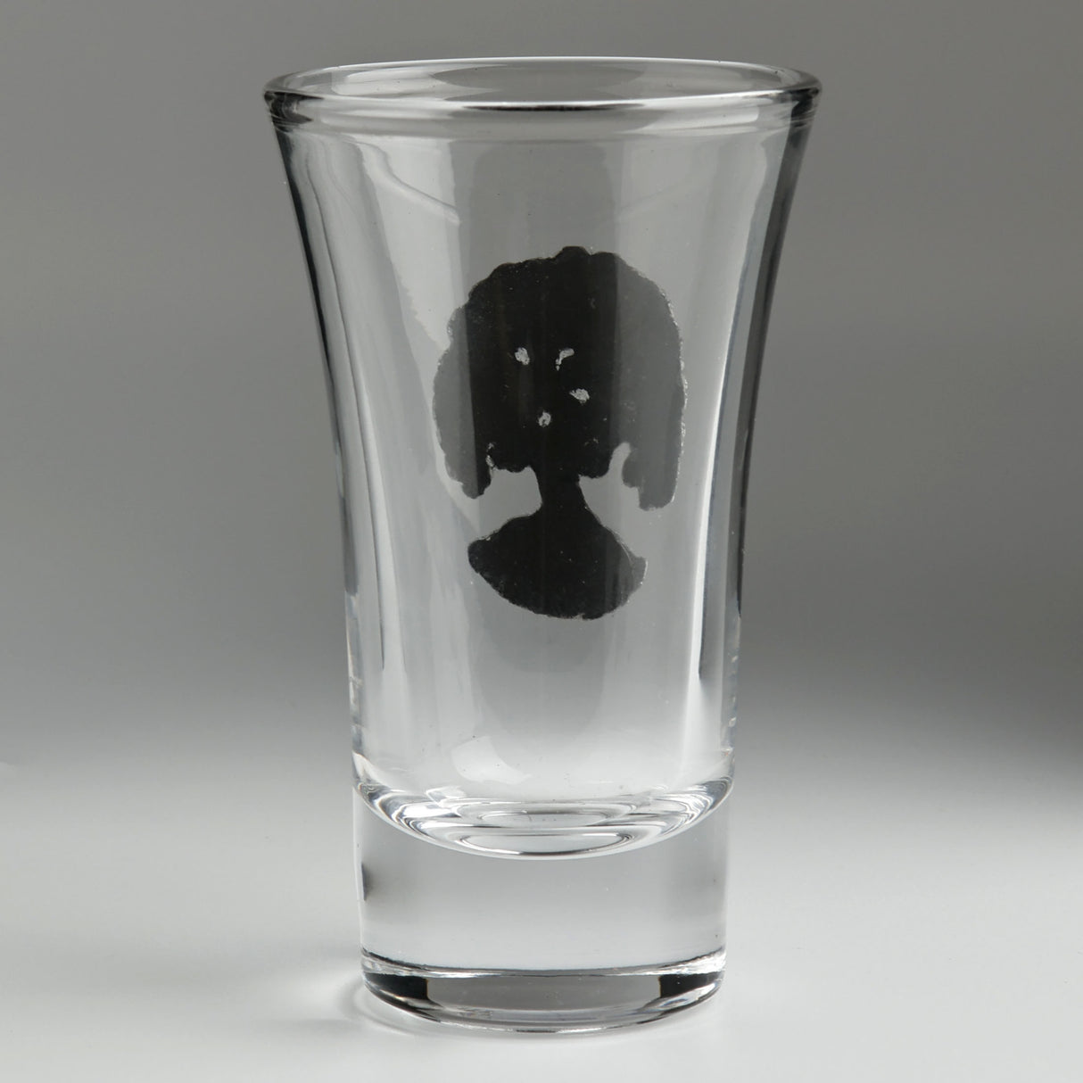 A clear glass shot glass featuring a detailed pewter tree of life emblem, shown from the back