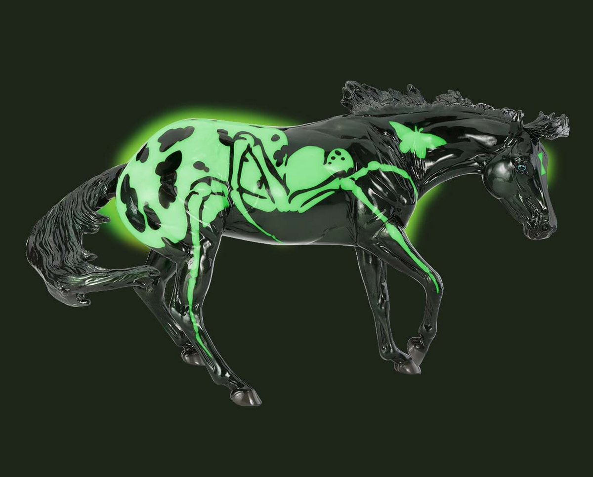 A glossy black horse figurine with a glowing neon green spider design, set against a solid dark green background.