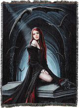A woven throw blanket featuring a dark gothic fantasy illustration of a red-haired vampire woman in a black dress seated on a coffin, with bats and a blue-lit archway in the background. The blanket has fringed edges and is shown flat against a white background.
