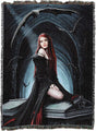 A woven throw blanket featuring a dark gothic fantasy illustration of a red-haired vampire woman in a black dress seated on a coffin, with bats and a blue-lit archway in the background. The blanket has fringed edges and is shown flat against a white background.