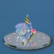 Glass figurine of a baby dragon with rainbow wings on a round base with rose, against a blue background