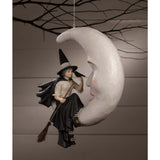 Hanging ornament with a witch on a moon, against a neutral background