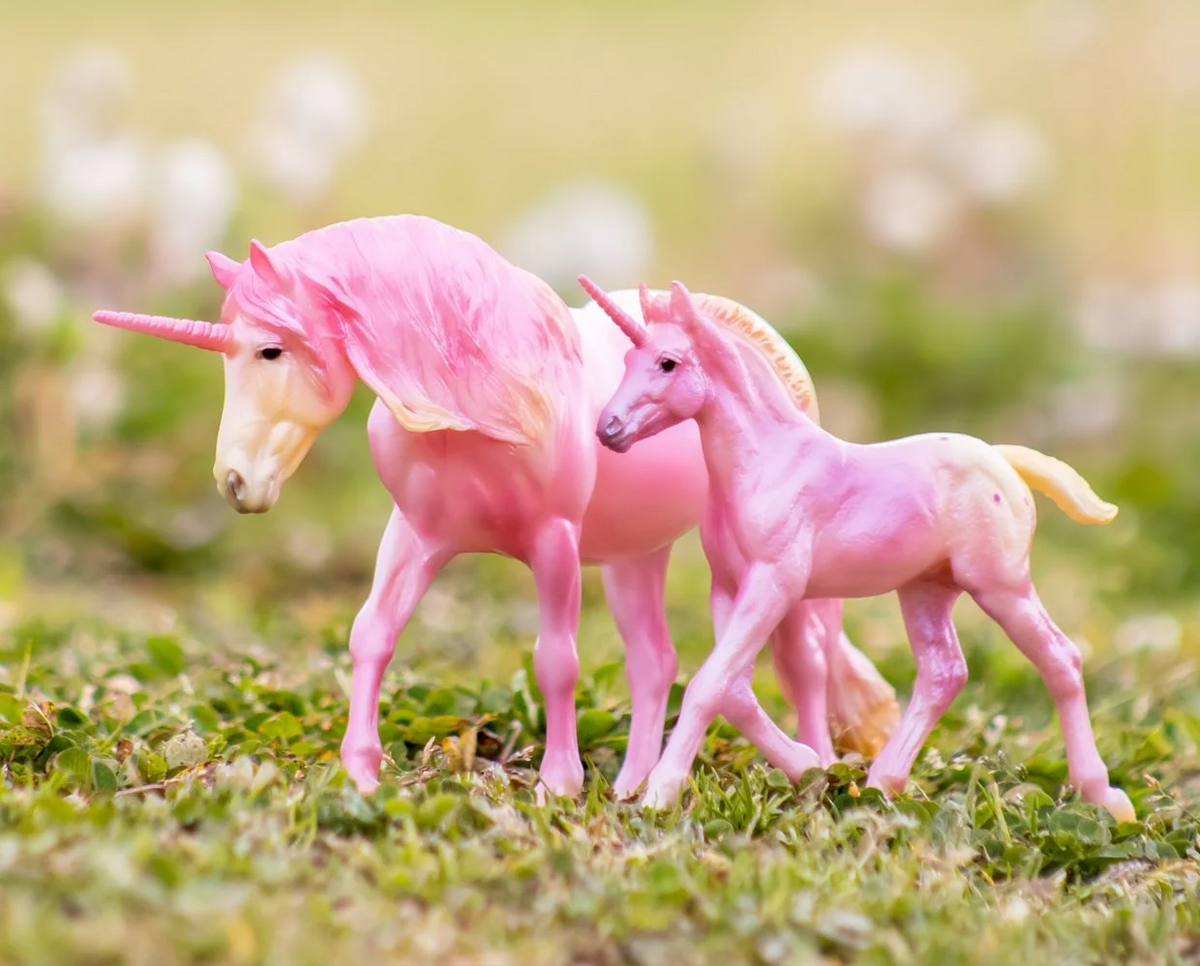 Model horse figurines, mare and foal, two appaloosa unicorns in pink and cream colors, shown in a grassy scene