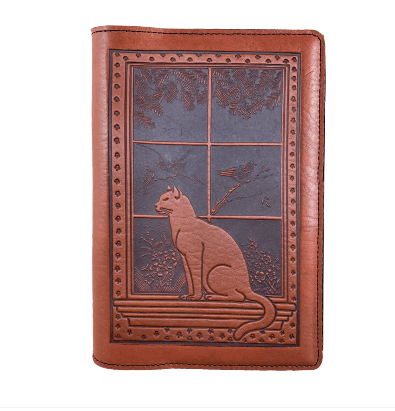 Leather notebook cover showing a cat sitting on a windowsill with birds, tree, flowers beyond. Shown in saddle brown.