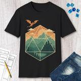 Black t-shirt with a geometric dice landscape design featuring a dragon, mountains, and a castle, shown with dice, papers, jeans