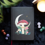 Black journal with moon and mushroom cover art, red ribbon bookmark