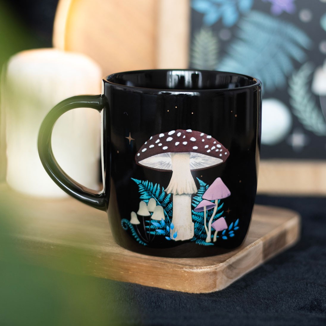 Black mug with mushroom design on a wooden coaster