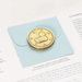 Lucky Duck coin, duck side shown in brass on packaging
