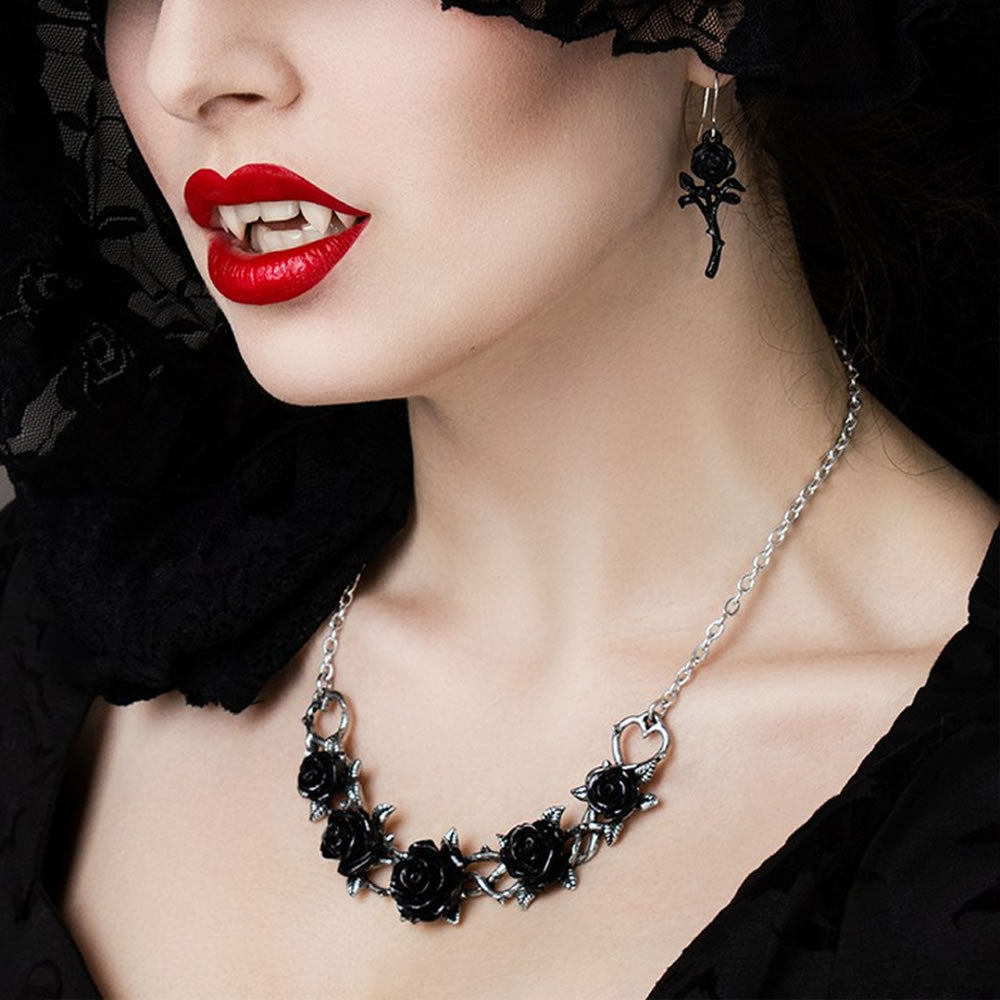 Close-up of a vampire woman wearing a black rose necklace and matching earrings with red lipstick.