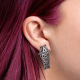 Pewter coffin earring worn by a person with pink hair