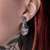 Pewter 'POISON' earring worn by a person with red hair and visible tattoos.