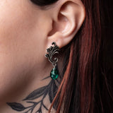 Close-up of an ear wearing a decorative earring with a green Austrian crystal