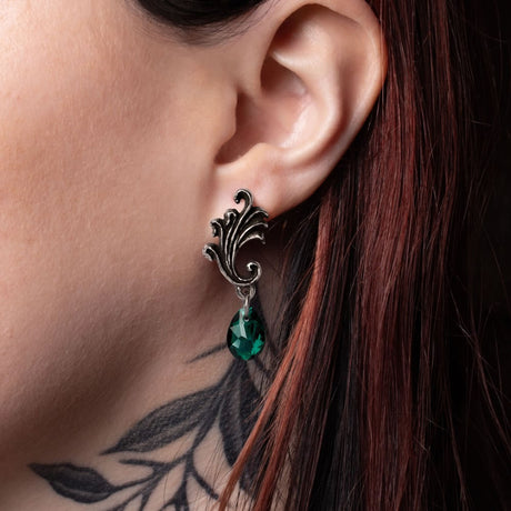 Close-up of an ear wearing a decorative earring with a green Austrian crystal