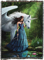 A woven tapestry featuring a fantasy illustration of a woman in a blue gown standing by a pond next to a white winged unicorn in a green forest.