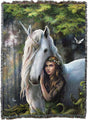Blanket with a design of a woman hugging a unicorn in a forest setting