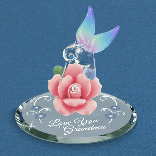 Figurine of a rainbow winged hummingbird with blue crystal eyes in glass, on a pink porcelain rose. Mirror base reads "Love You Grandma"
