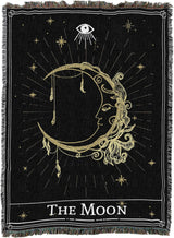 Decorative blanket with celestial design featuring 'The Moon' and eye symbol on black background