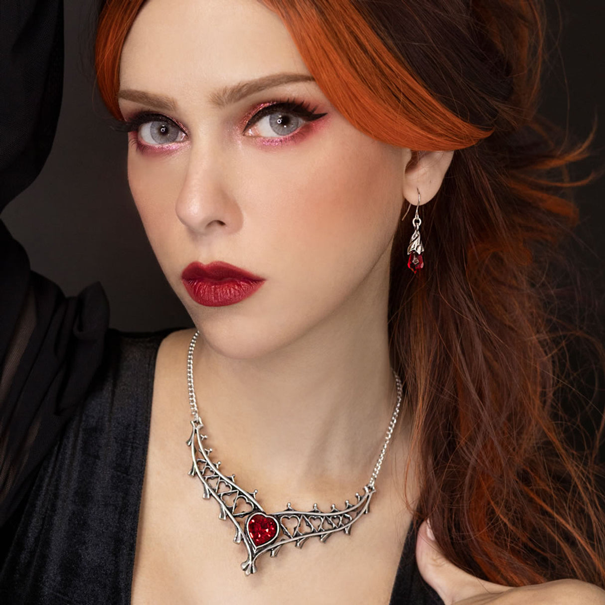 Woman with red hair wearing a pewter necklace with a red heart pendant.