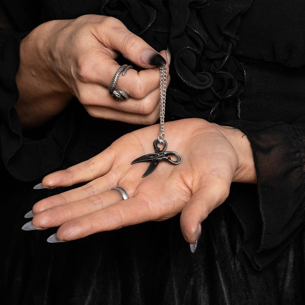 Blackened pewter scissors pendant on a chain, shown held