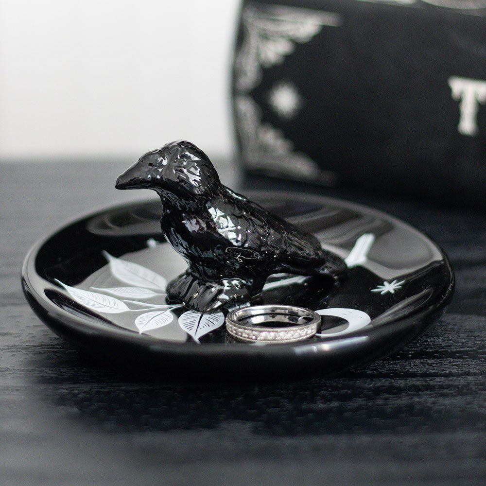 Black ceramic dish with a raven bird design, leaves and moon, shown with ring