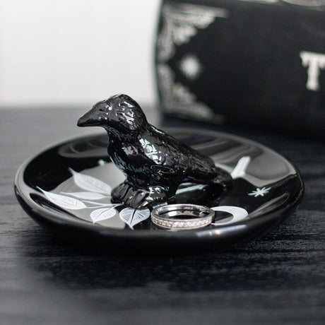 Black ceramic dish with a raven bird design, leaves and moon, shown with ring