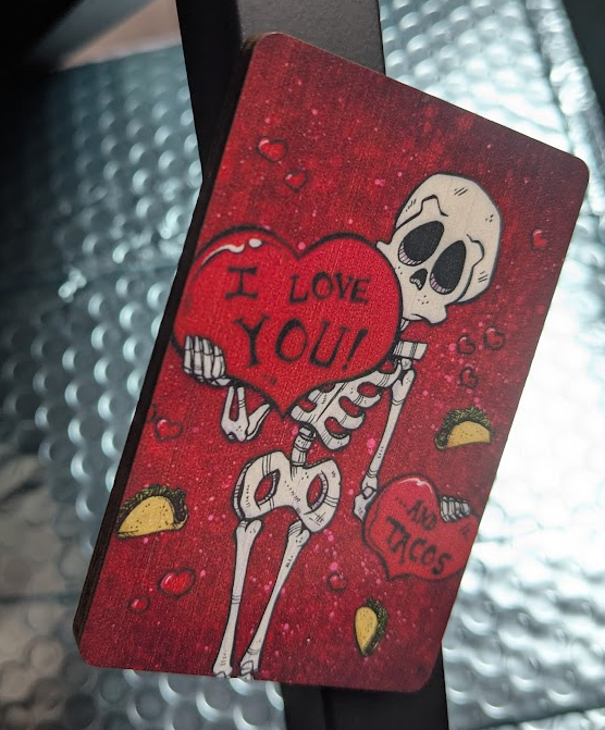 Magnet of a skeleton holding a heart that says "I LOVE YOU!" and in the background are tacos and another heart that says "...AND TACOS"
