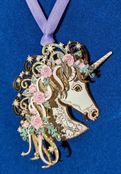 Brass ornament of a white unicorn bust with pink roses and green leaves