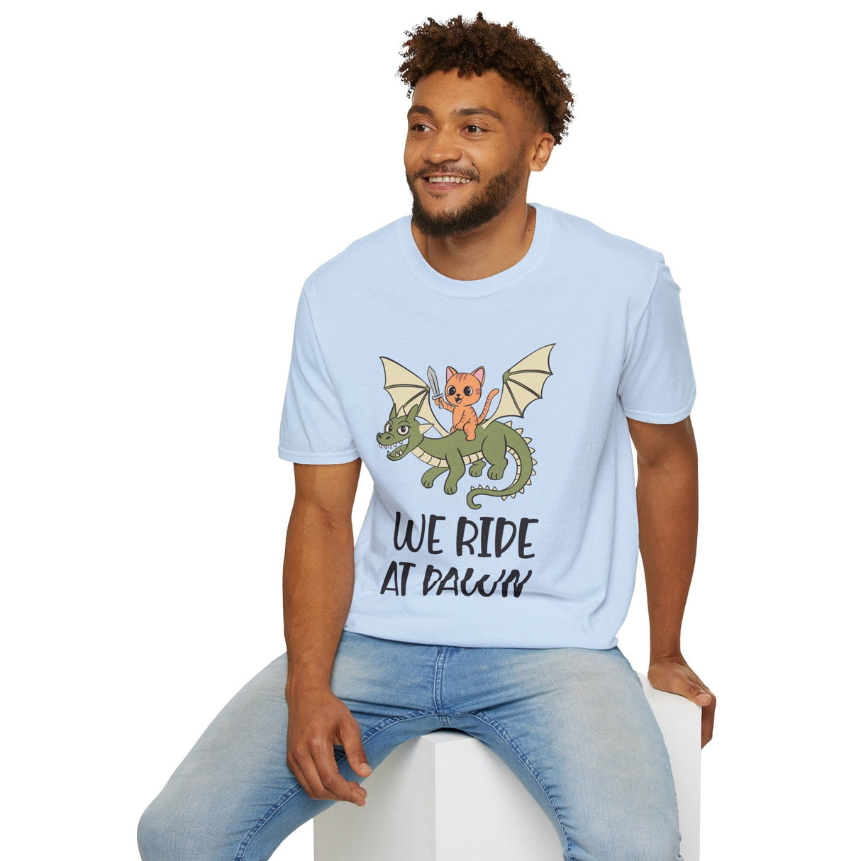 Man wearing blue t-shirt with a cat riding a dragon graphic and 'We Ride at Dawn' text