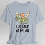 Light blue t-shirt with a cat riding a dragon graphic and 'We Ride at Dawn' text
