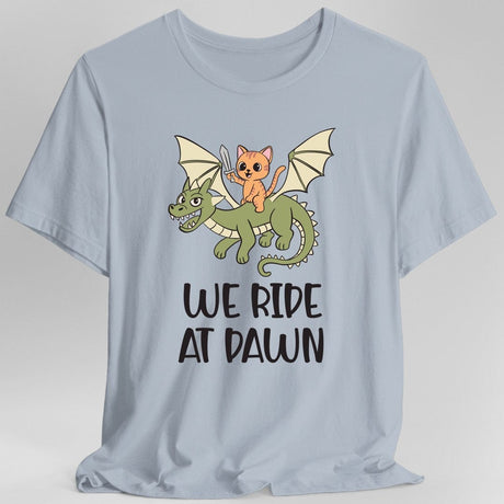 Light blue t-shirt with a cat riding a dragon graphic and 'We Ride at Dawn' text