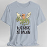 Light blue t-shirt with a cat riding a dragon graphic and 'We Ride at Dawn' text