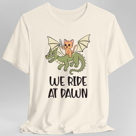 Cream t-shirt with a cat riding a dragon graphic and 'We Ride at Dawn' text