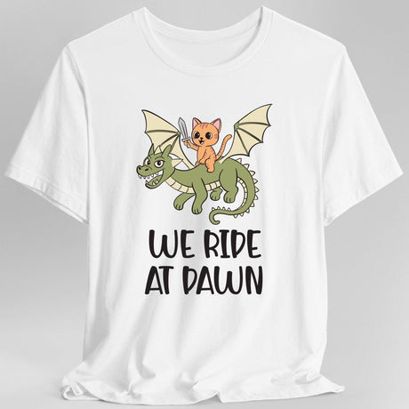 White t-shirt with a cat riding a dragon graphic and 'We Ride at Dawn' text