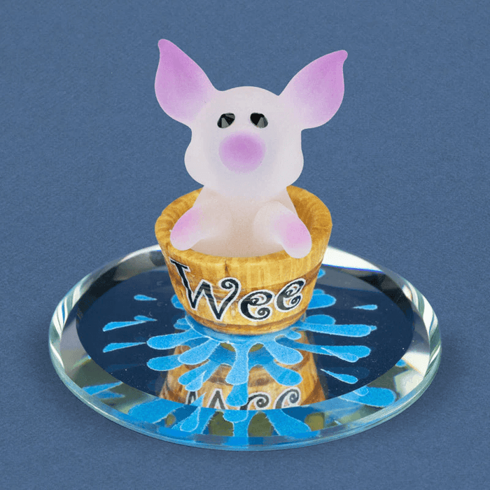 Glass figurine of pink frosted pig in a bucket that says "Wee" on a mirror with water decorations