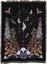 Decorative blanket with spider web, flowers, and moons design on a black background