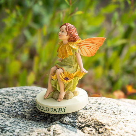 Flower fairy figurine of a pixie in pale green with yellow flower accents and peach-orange wings. Base says "Marigold Fairy"