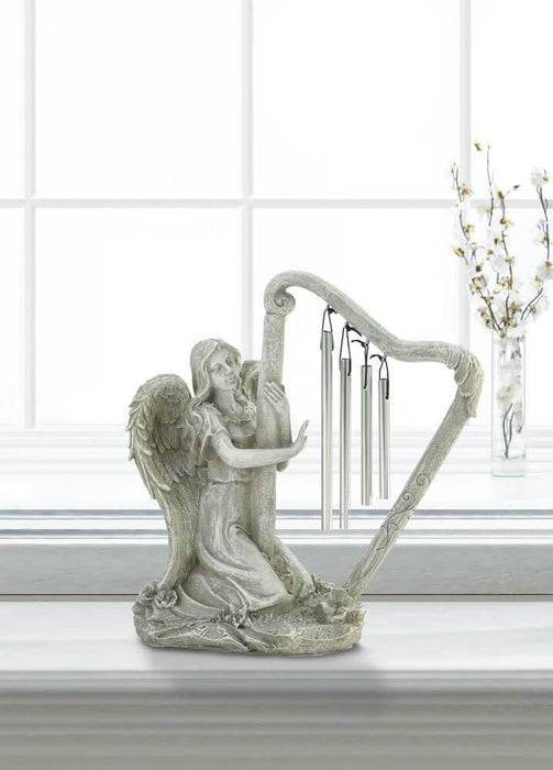 Angel with wind chime harp displayed on a sunny windowsill