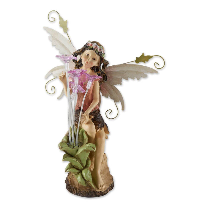 Solar powered fairy figurine shows of a pixie in pink admiring tall flowers