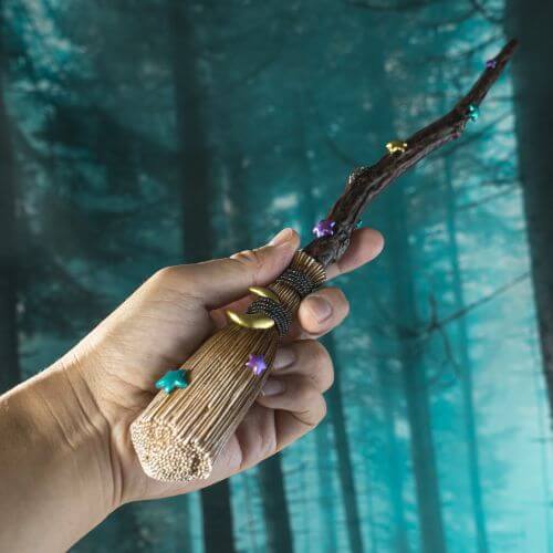 Witch's Broom magic wand with colorful stars and a gold moon. Shown held