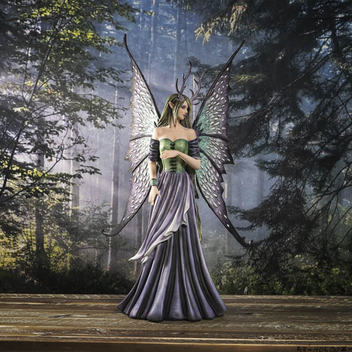 Large fairy figurine in shades of blue, purple, green and teal. Fairy has spotted wings, long hair and antlers. Shown in a forest setting