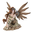 Steampunk fairy figurine with mechanical bronze wings and red hair. Goggles on her head and a striped outfit. She sits on a rock, gazing out.