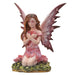 Fairy with pink dress and wings, with hearts on wings. She holds a heart and sits next to rose flowers on the grass.