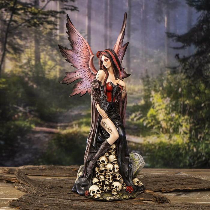 Gothic fairy on skulls shown in a forest setting on a wood table