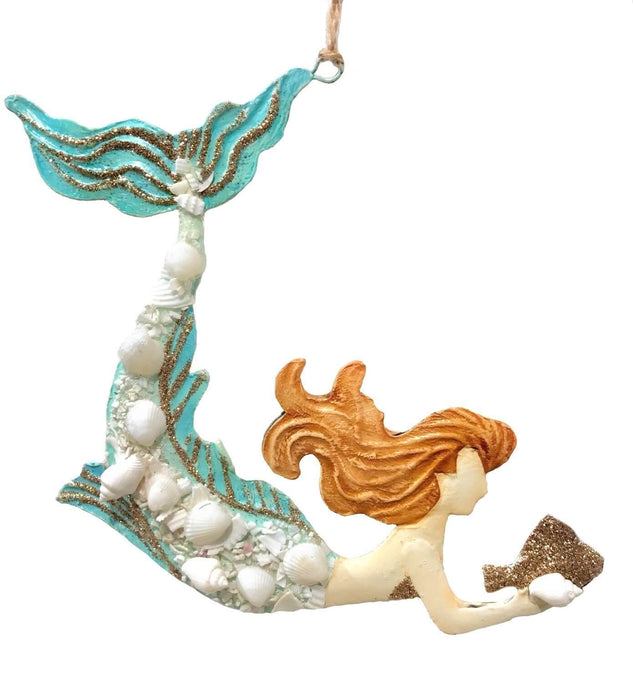 Ornament of a mermaid holding a glittery gold fish. The siren is done in blue with sandy blond hair and she is accented in seashells and gold glitter