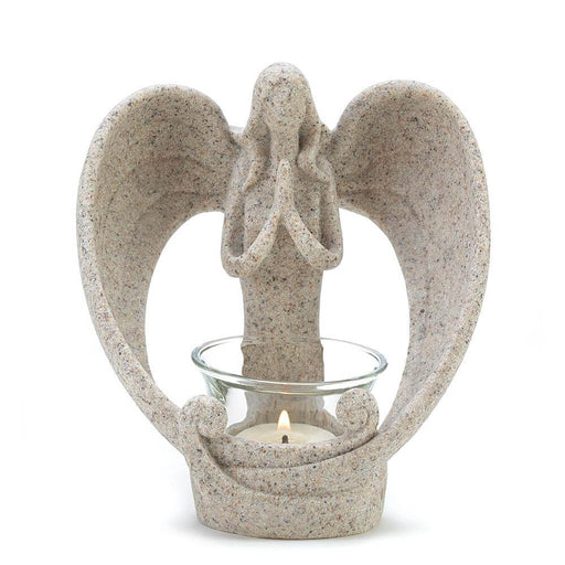 Stone look angel with curling wings praying above a candle