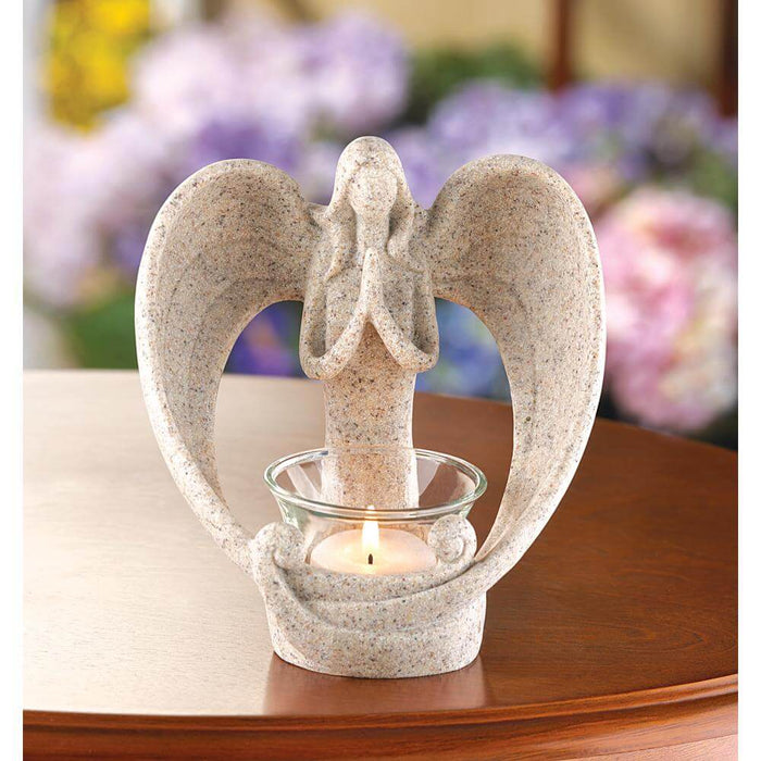 Stone look angel candle holder shown lit on a wooden table